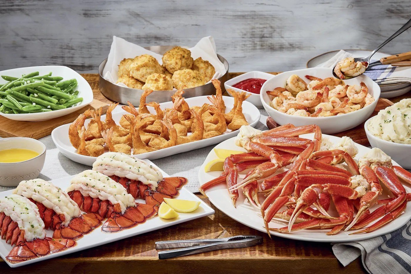 Seafood feast with lobster tails, snow crab legs, crispy shrimp, shrimp scampi, Cheddar Bay Biscuits, green beans, and mashed potatoes